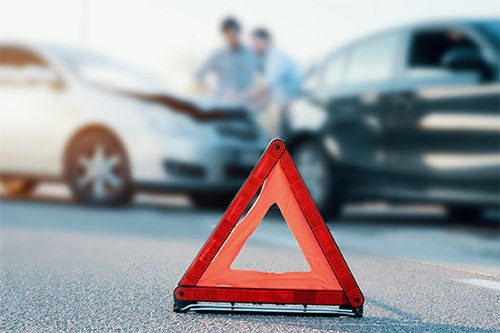 Car Accidents — Warning Triangle And Traffic Collision In Background in Athens, GA