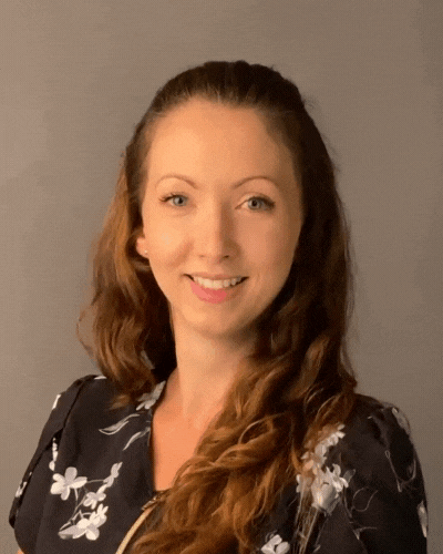 A woman in a black and white floral shirt is smiling for the camera.