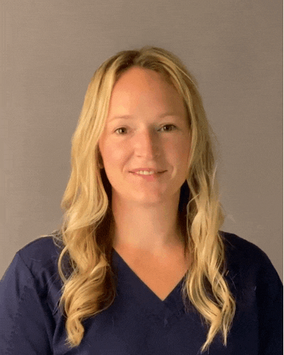 A woman with blonde hair is wearing a blue shirt and smiling for the camera.