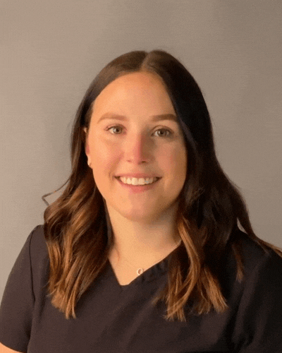 A woman in a black scrub top is smiling for the camera.