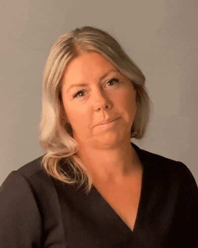 A woman with blonde hair is wearing a black shirt and looking at the camera.