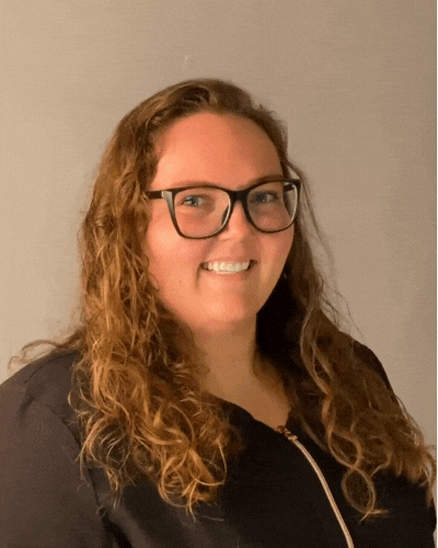 A woman wearing glasses and a black shirt is smiling for the camera.