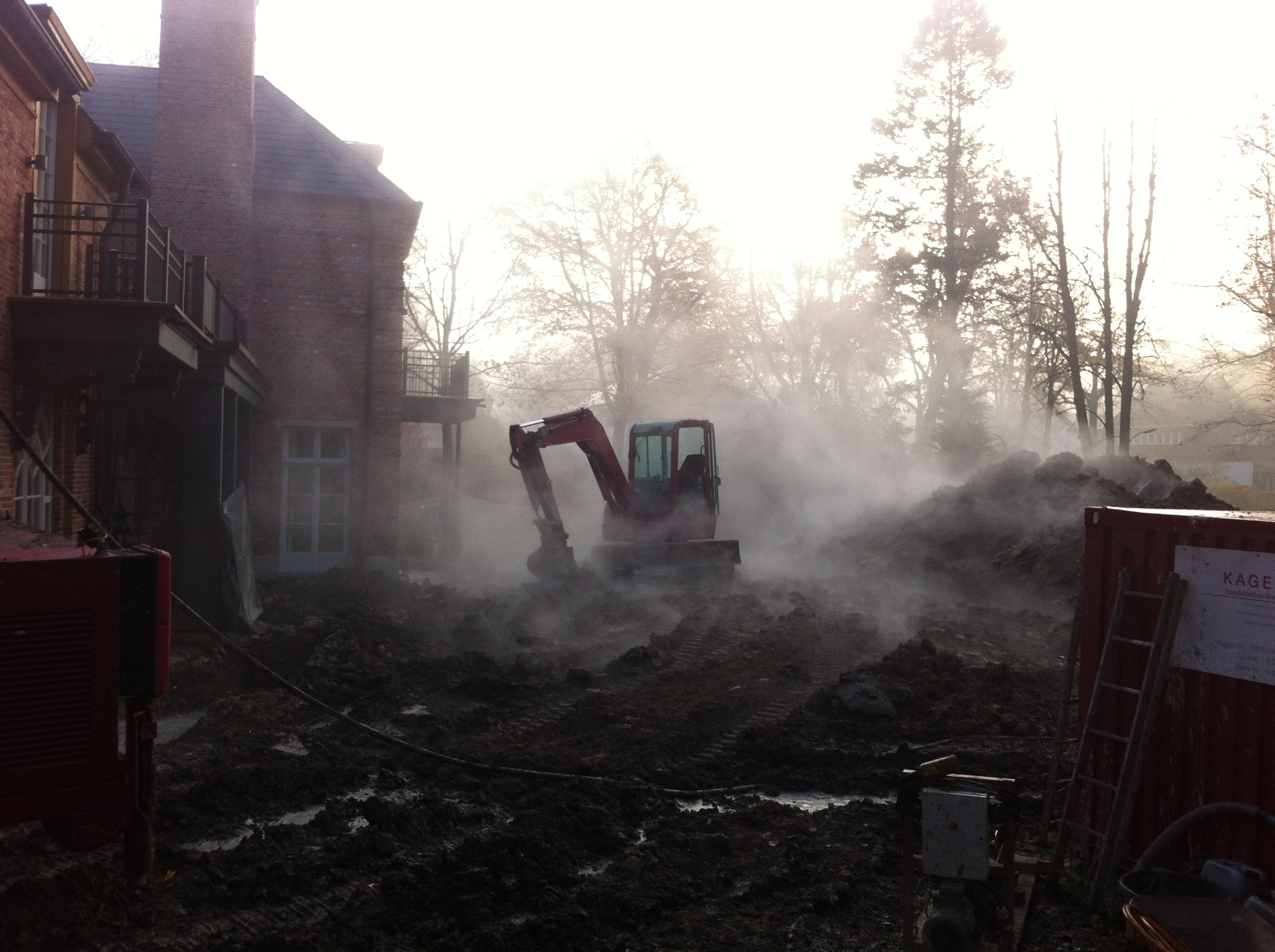 Ein roter Bagger bewegt Erde vor einem Haus