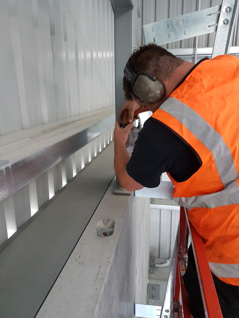 man in orange vest drilling