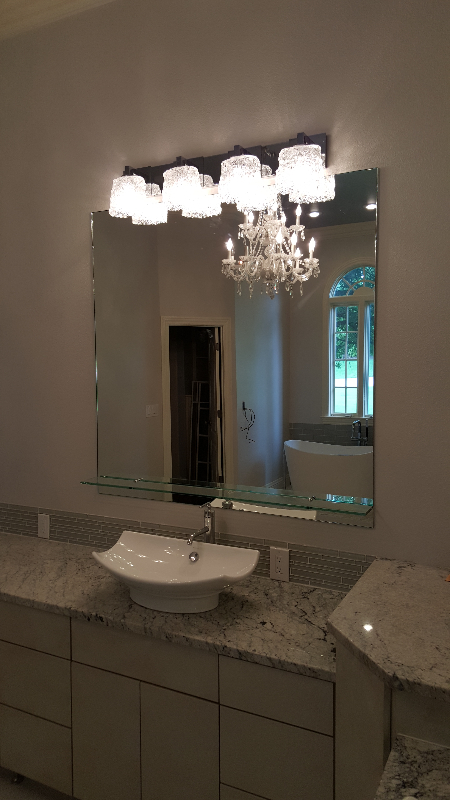 Bathroom with large mirror, vanity, modern sink, and chandelier reflection.