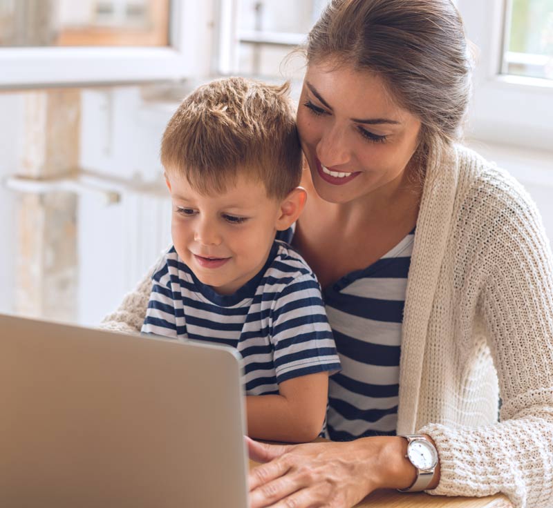 son on mother's lap with computer