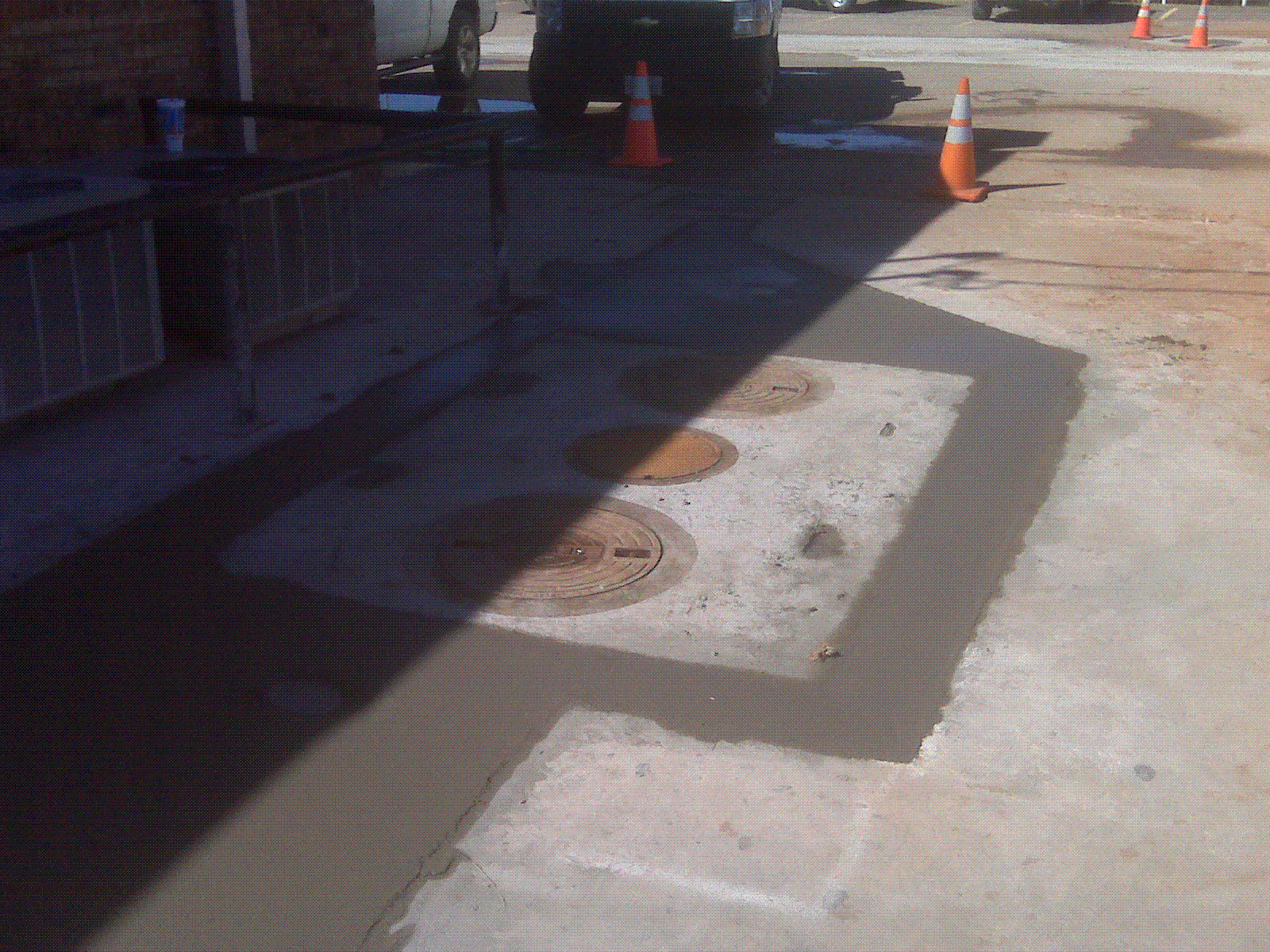 A manhole cover is being repaired on the sidewalk