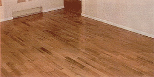 Wooden hardwood floor in a room with white walls and trim.