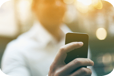 Person in a white shirt holding a smartphone, using their finger to interact with the screen.