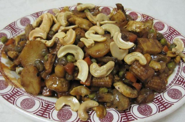 Cashew chicken and vegetables on a plate, garnished with cashews.