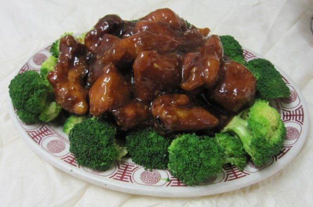 General Tso chicken with broccoli florets on a patterned plate.