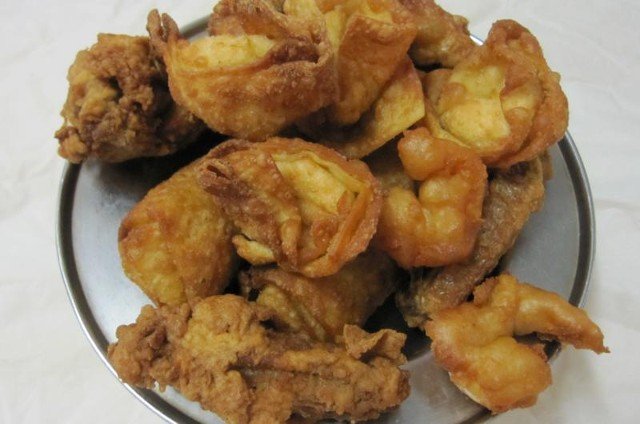 A plate of golden-brown fried wontons, some in a folded shape, some round.