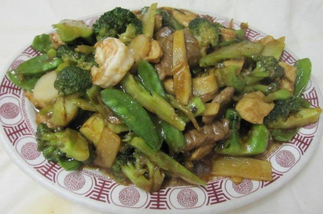 Vegetable stir-fry with broccoli, snap peas, mushrooms, and shrimp on a patterned plate.