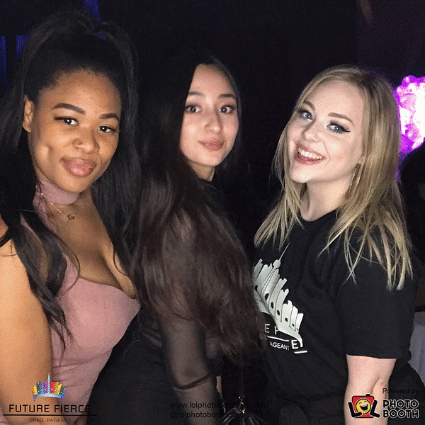 Three women are posing for a photo in front of a sign that says future peace
