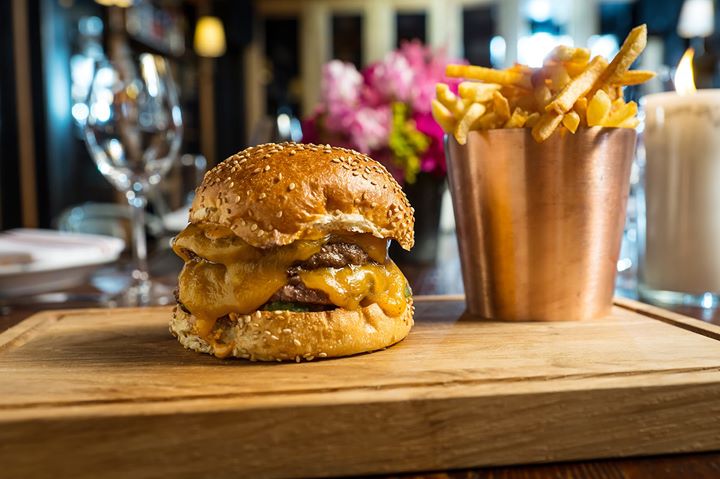 A hamburger and french fries are on a wooden cutting board.