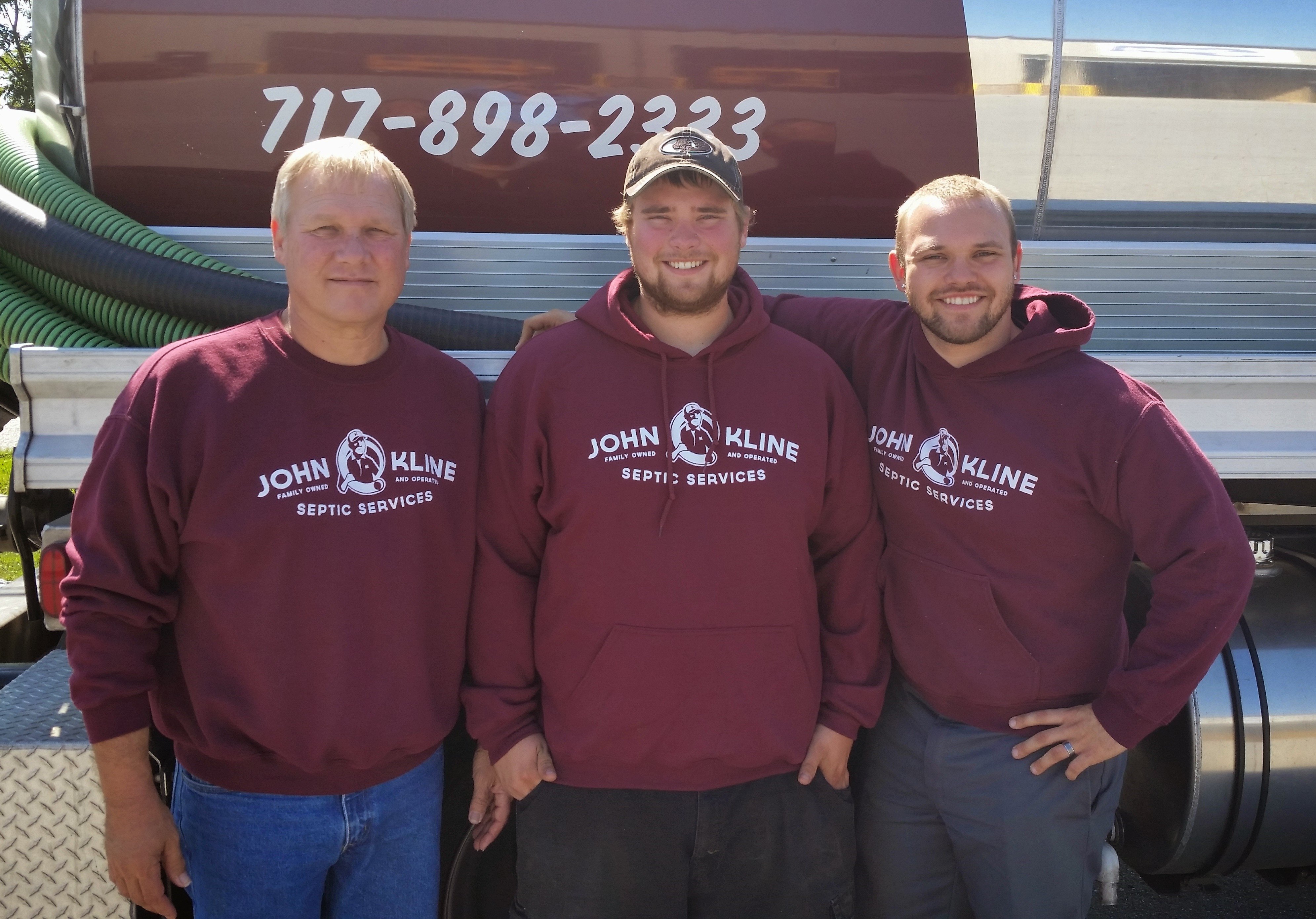 Three men are posing in front of a truck that says 712-898-2323