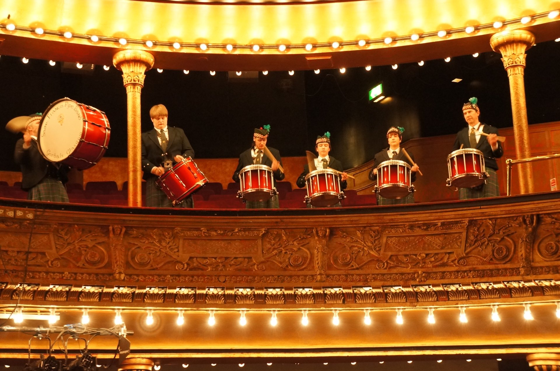 a group of men are playing drums in an auditorium