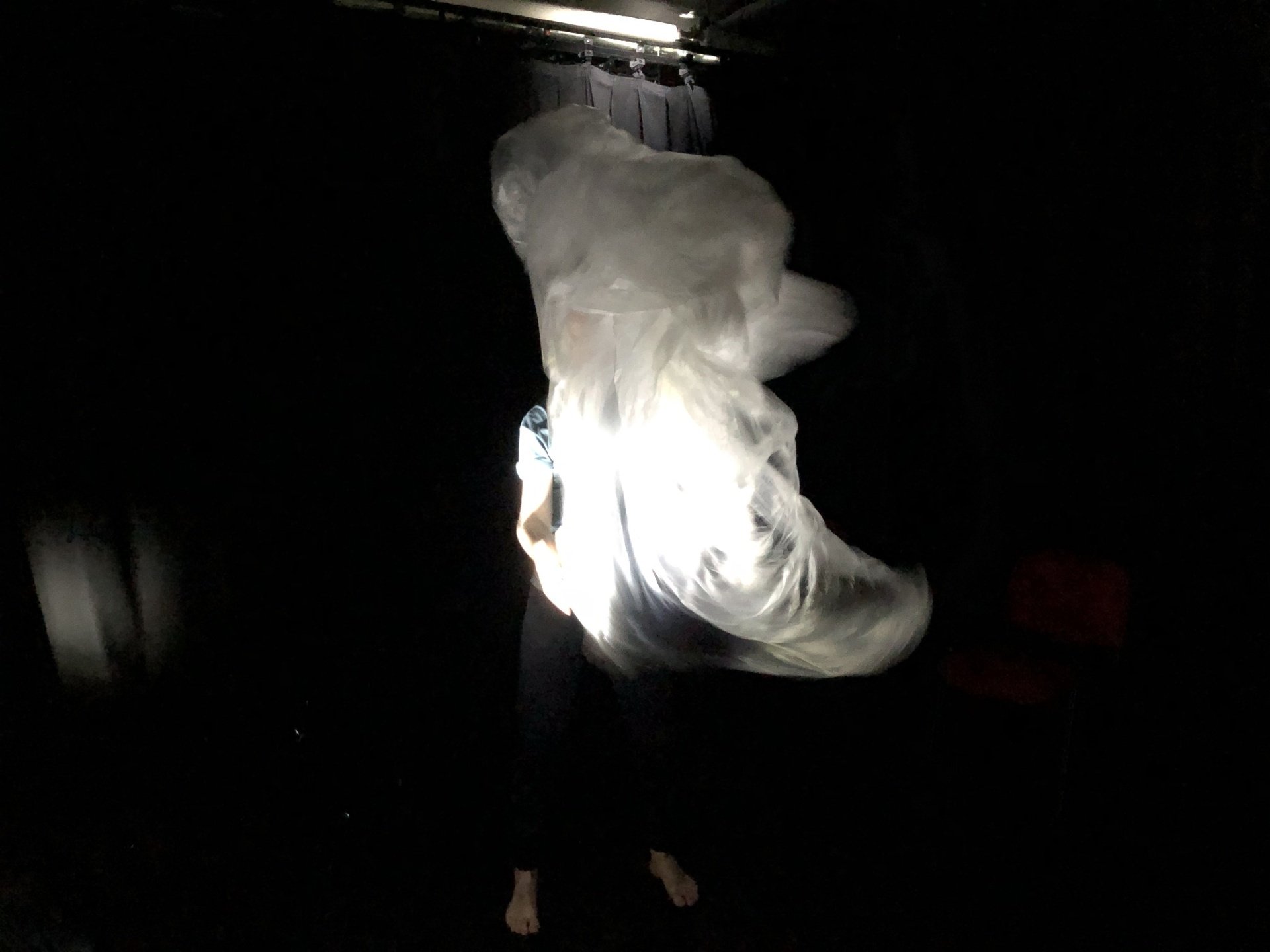 a person is standing in the dark with a light shining on them .