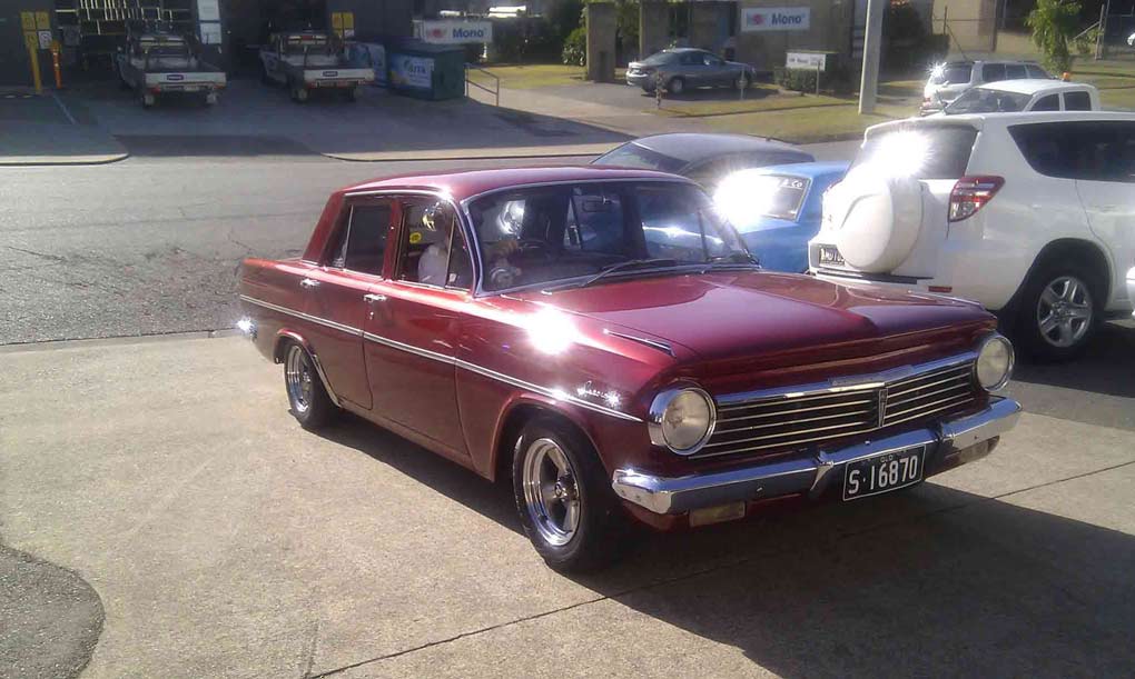 an old maroon car with headlights