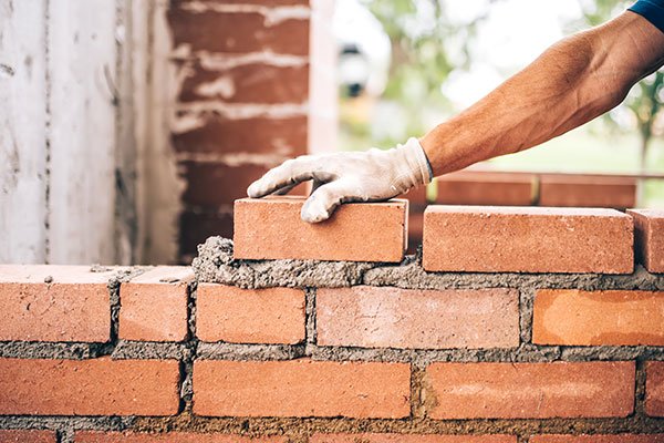 Bricklayer worker placing bricks on cement