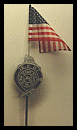 An american flag is hanging from a pole next to a firefighter badge.