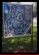 A map of a park is on a pole in the grass.