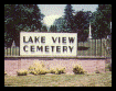 A sign for lake view cemetery is sitting in the grass.