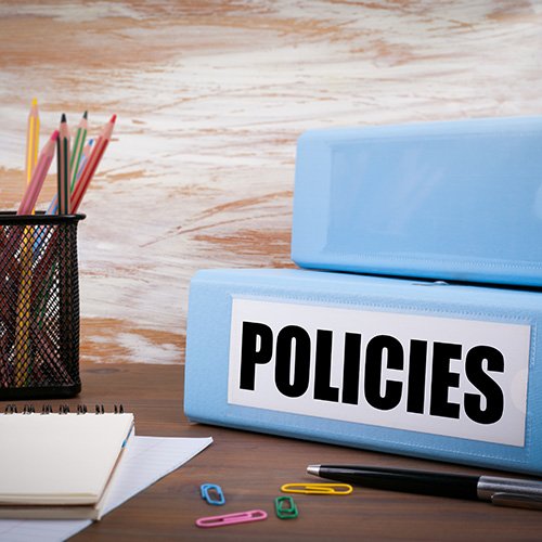 policies binder on desk with other supplies