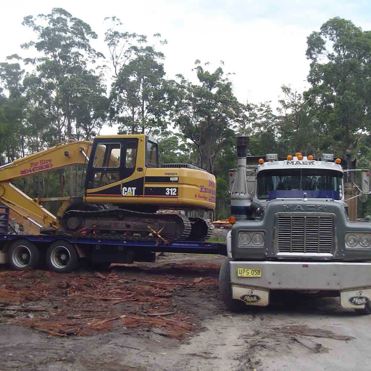 yellow bob cat being hauled by a large truck