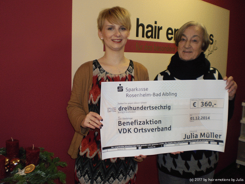 Zwei Frauen halten einen Scheck vor einem Schild mit der Aufschrift „Haare“