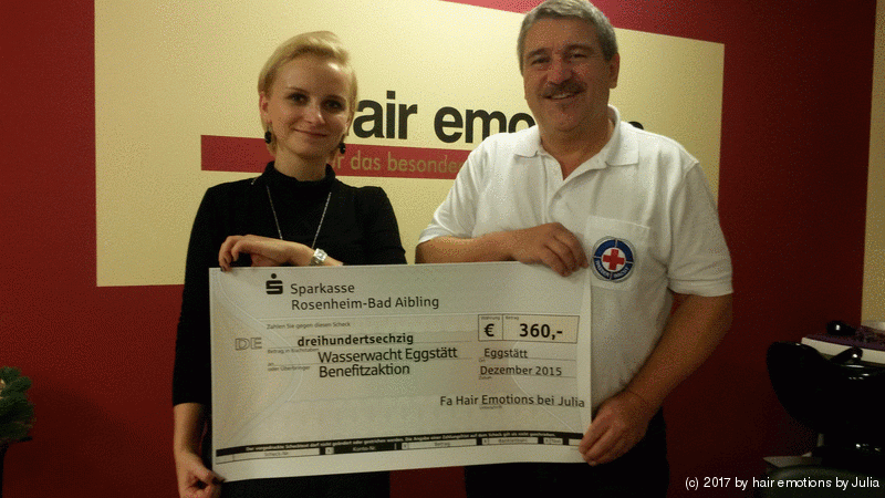 Ein Mann und eine Frau halten einen Scheck vor einem Schild mit der Aufschrift „Air Em“