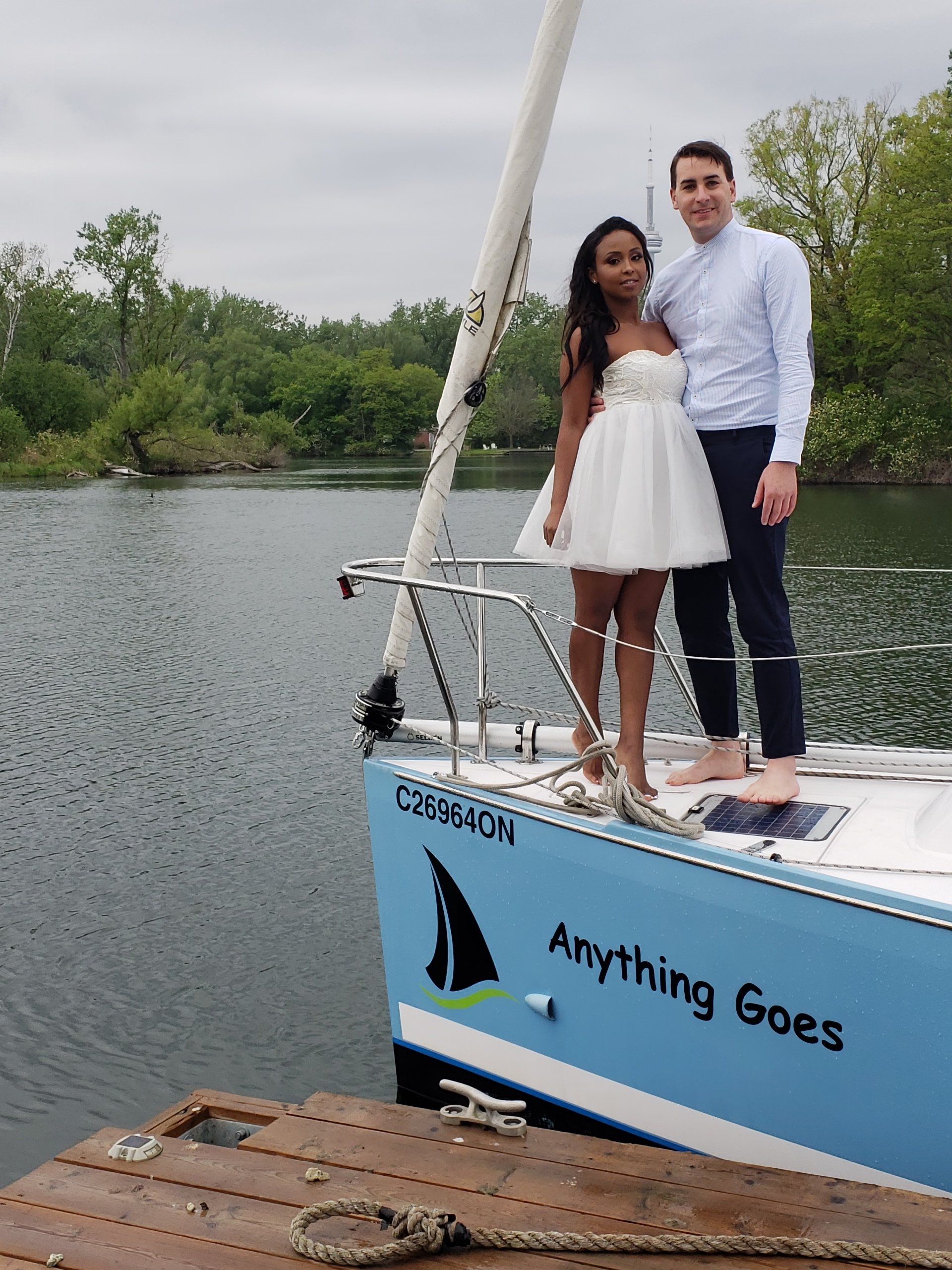 Couple standing on top of the bow of a siling boat