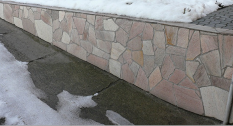 Kamienna ściana wzdłuż chodnika ze śniegiem na ziemi