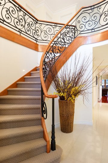 curving staircase with wooden and steel railing