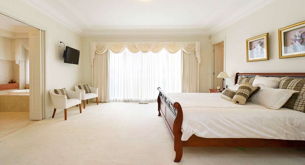 large open bedroom with light coming in through curtains in front of window