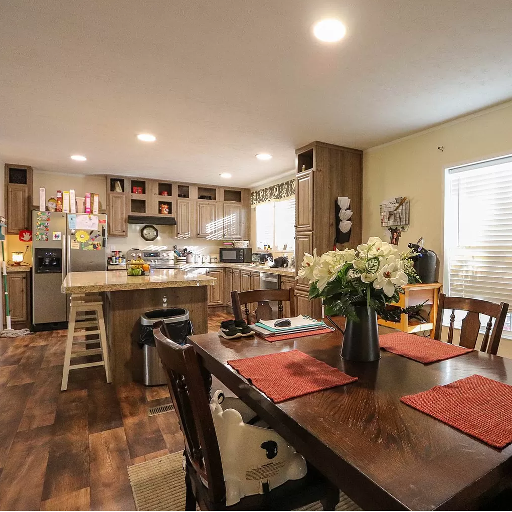 A kitchen with a table and chairs and a vase of flowers on the table.