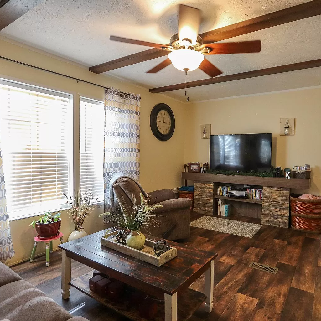 A living room with a ceiling fan and a flat screen tv