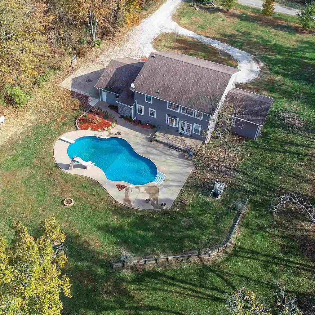An aerial view of a house with a large swimming pool in the backyard.