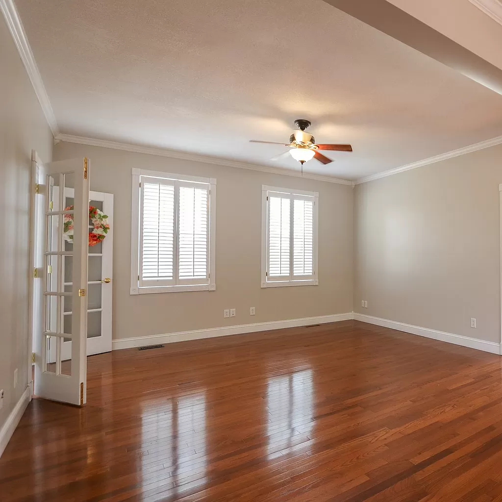 An empty living room with hardwood floors and a ceiling fan