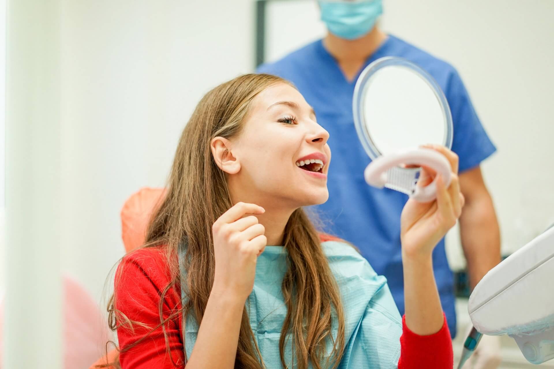 Girl checking her teeth after orthodontic treatment