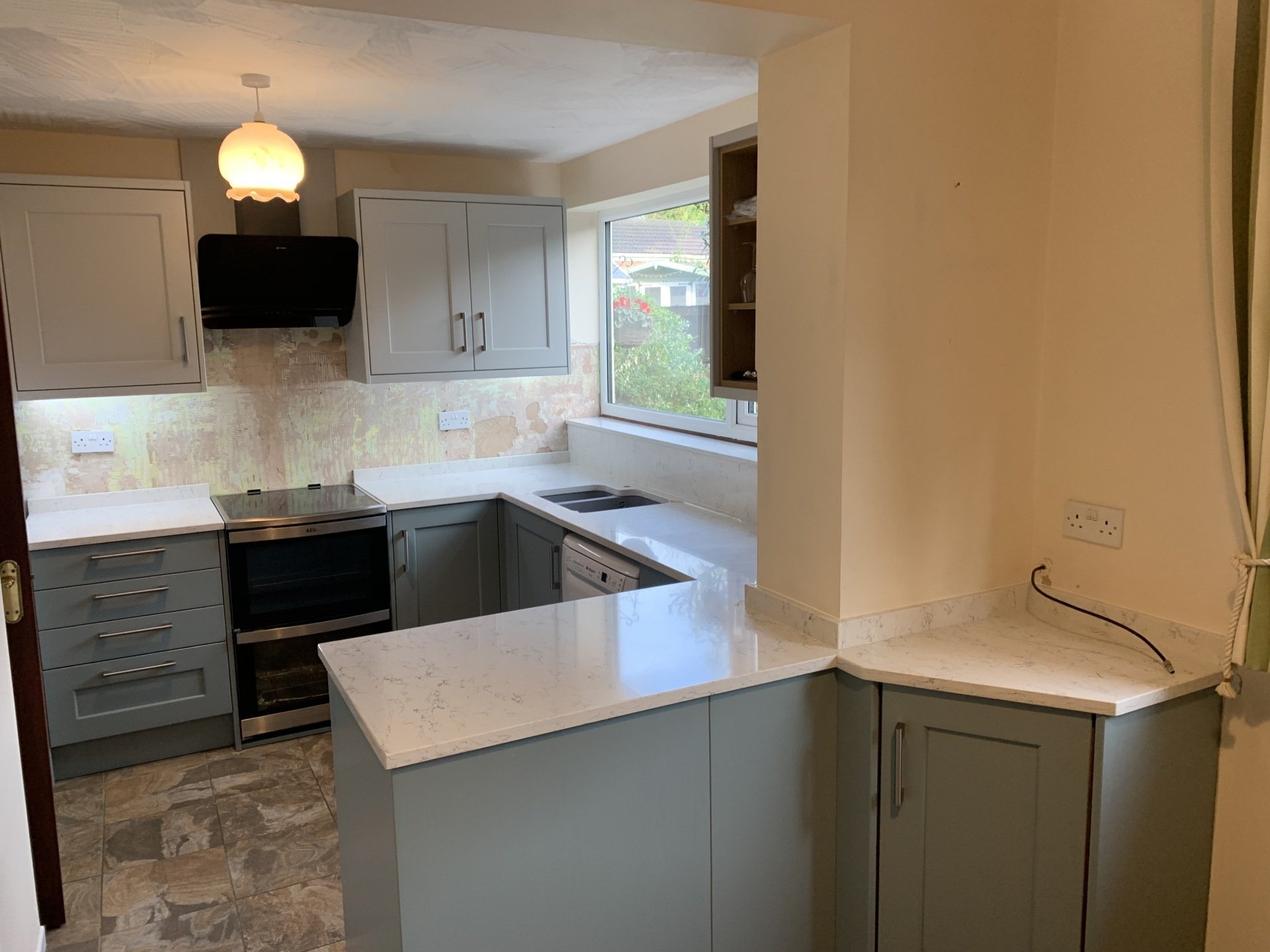 A new solid surface kitchen counter top corner with a wine cooler below and hardwood floor.