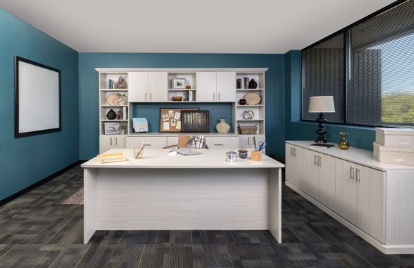 A room with blue walls and white cabinets and a desk
