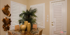 A dining room with a table and chairs and a potted plant on the table.