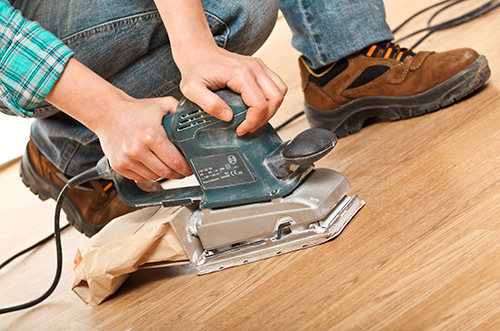  carpenter at work with sander on wood floor