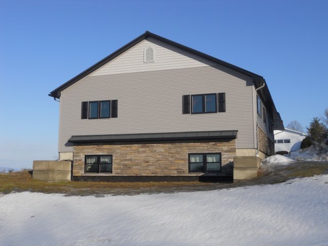 A house with a lot of windows is sitting on top of a snow covered hill