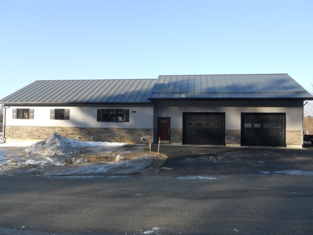 A house with two garage doors and a metal roof