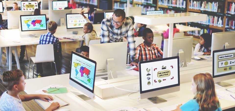 children on computers with teacher