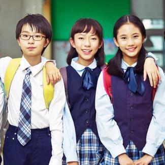 Three children in school uniforms are posing for a picture together.