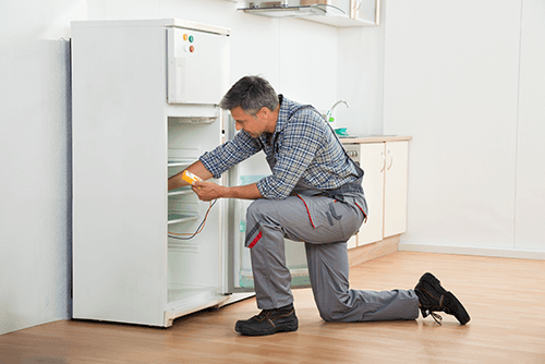 Experienced electrician repairing refrigerator