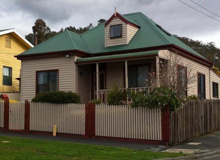 A home with a white fence and green roof